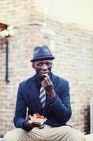 schwarzer Mann isst auf einer Straße foto