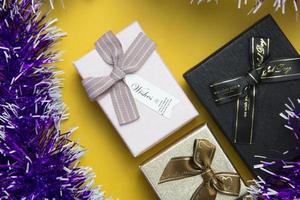 satz von drei geschenkboxen und lila bändern auf gelbem hintergrund, weihnachten, neujahrskonzepte partydesign. foto