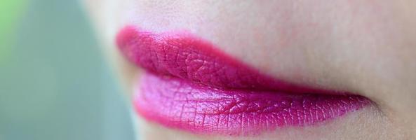 Nahaufnahme von Frauenlippen mit glänzendem fuchsiafarbenem Lippenstift foto