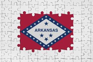 Arkansas US-Staatsflagge im Rahmen aus weißen Puzzleteilen mit fehlendem Mittelteil foto