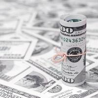 us-dollar aufgerollt und mit band festgezogen liegt auf vielen amerikanischen banknoten mit verschwommenem hintergrund foto