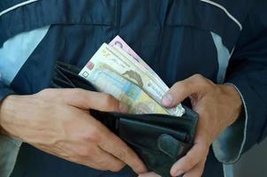 nahaufnahme männliche hände öffneten die brieftasche oder geldbörse mit ukrainischer geldwährung hryvnia foto