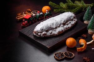 weihnachtstortenstollen mit marzipan, beeren und nüssen auf dunklem betonhintergrund foto