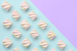 bunter Marshmallow auf violettem und blauem Papierhintergrund. pastellfarbenes, kreatives Strukturmuster. minimal foto