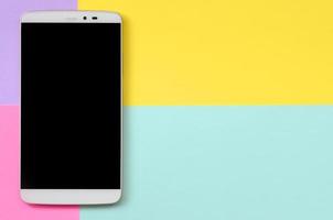 modernes smartphone mit schwarzem bildschirm auf texturhintergrund von modepastellblauem, gelbem, violettem und rosafarbenem papier in minimalem konzept foto