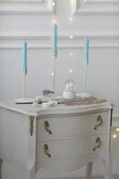 Nachttisch aus weißem Holz, Kommode im Schlafzimmer. Kerzen auf dem Nachttischinnenraum. Möbelserie. modernes Design