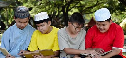 Eine Gruppe muslimischer Jungen sitzt zusammen unter dem Baum im Schulpark, sie lesen, lernen, reden, schlagen vor und beraten sich gegenseitig über Lernprobleme, weicher und selektiver Fokus. foto