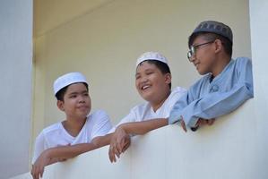 junge asiatische muslimische jungen nehmen sich zeit mit ihren freunden auf dem balkon einer moschee oder einer religiösen schule, weicher und selektiver fokus. foto