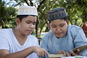 asiatische muslimische jungen sitzen im schulpark zusammen, um zu lesen und ihre täglichen aktivitäten zu lernen und in ihrer freizeit hausaufgaben zu machen, bevor sie nach hause zurückkehren, weicher und selektiver fokus. foto