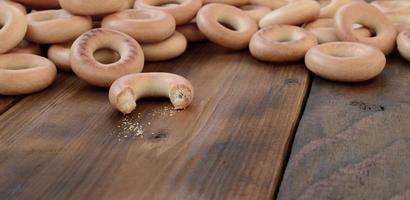 viele frische gelbe bagels liegen auf der oberfläche des alten dunklen holzes. eine beliebte Art von Mehlprodukten. eine der traditionellen russischen Leckereien für Tee foto