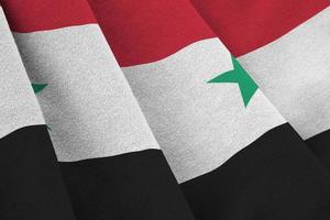 syrische flagge mit großen falten, die unter dem studiolicht im innenbereich wehen. die offiziellen symbole und farben im banner foto