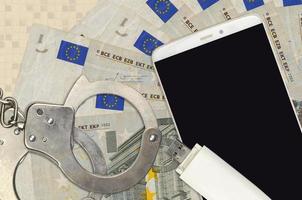 5-Euro-Scheine und Smartphone mit Polizeihandschellen. Konzept von Hacker-Phishing-Angriffen, illegalem Betrug oder weicher Verteilung von Malware foto