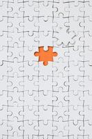 die Textur eines weißen Puzzles im zusammengebauten Zustand mit einem fehlenden Element, das einen orangefarbenen Raum bildet foto