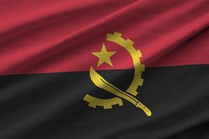 angola-flagge mit großen falten, die unter dem studiolicht im innenbereich wehen. die offiziellen symbole und farben im banner foto