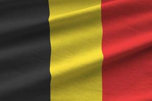 belgische flagge mit großen falten, die in der nähe unter dem studiolicht im innenbereich wehen. die offiziellen symbole und farben im banner foto