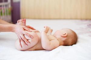 Mama macht Gymnastik für ein Kind. mutter massiert baby im bett zu hause foto