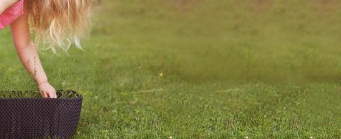 süßes kleines Mädchen, das Blumen im Sommergarten gießt. Banner foto