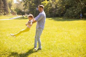 Vater mit Tochter, die Spaß auf dem Gras im Park hat foto