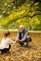 Großvater verbringt am Herbsttag Zeit mit seiner Enkelin im Park foto
