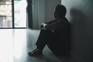 Schizophrenie mit einsamem und traurigem Depressionskonzept der psychischen Gesundheit. depressive frau, die zu hause an der wand sitzt, mit einem schatten an der wand, der sich elend fühlt. Frauen sind depressiv, ängstlich und unglücklich. foto