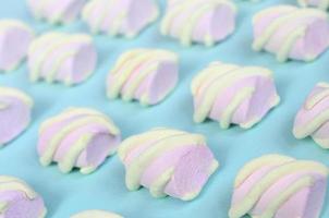 bunter Marshmallow auf blauem Papierhintergrund ausgelegt. pastellfarbenes, kreatives Strukturmuster. perspektivische Makroaufnahme foto