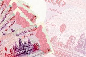 500 kambodschanische Riels-Scheine liegen im Stapel auf dem Hintergrund einer großen halbtransparenten Banknote. abstrakter betriebswirtschaftlicher hintergrund foto