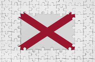 Alabama US-Staatsflagge im Rahmen aus weißen Puzzleteilen mit fehlendem Mittelteil foto