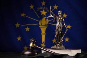 Indiana US-Staatsflagge mit Statue von Lady Justice, Verfassung und Richterhammer auf schwarzem Vorhang. Begriff von Urteil und Schuld foto