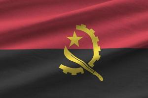 angola-flagge mit großen falten, die unter dem studiolicht im innenbereich wehen. die offiziellen symbole und farben im banner foto