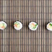 Sushi-Rollen liegen auf einer Nähmatte aus Bambusstroh. traditionelles asiatisches essen. Ansicht von oben. flacher Laienminimalismus mit Kopierraum foto