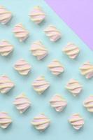 bunter Marshmallow auf violettem und blauem Papierhintergrund. pastellfarbenes, kreatives Strukturmuster. minimal foto