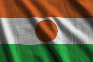 niger-flagge mit großen falten, die im innenbereich unter dem studiolicht wehen. die offiziellen symbole und farben im banner foto