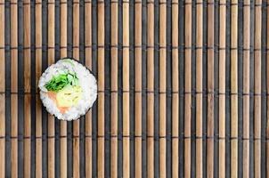 Sushi-Rolle liegen auf einer Nähmatte aus Bambusstroh. traditionelles asiatisches essen. Ansicht von oben. flacher Laienminimalismus mit Kopierraum foto