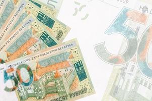 50 weißrussische Rubelscheine liegen im Stapel auf dem Hintergrund einer großen halbtransparenten Banknote. abstrakter betriebswirtschaftlicher hintergrund foto