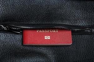Reisepass schaut aus der Tasche einer schwarzen Ledertasche, Nahaufnahme, Makro handgefertigt, natürliche Materialien. foto