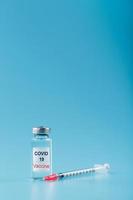 spritze und ampulle mit einem impfstoff gegen das covid-19-virus gegen krankheiten auf blauem hintergrund. foto