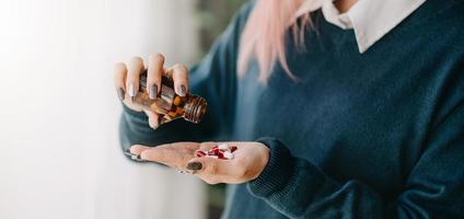 Depression einer Frau, die eine Flasche mit Pillen in der Hand hält, um die verschriebenen Medikamente einzunehmen foto