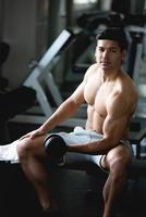 junger mann trainiert, hebt mit hantel, um muskeln in der fitness im fitnessstudio aufzubauen. foto