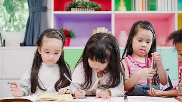 gruppe von kindern, die im klassenzimmer zeichnen, multiethnische junge jungen und mädchen, die fröhlich lustig lernen und spielen, malen auf papier in der grundschule. kinder zeichnen und malen im schulkonzept. foto