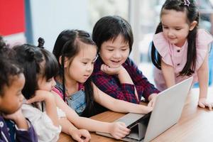 gruppe von kindern, die laptop im klassenzimmer verwenden, multiethnische junge jungen und mädchen, die glücklich sind, technologie für das studium in der grundschule zu nutzen. kinder nutzen technologie für das bildungskonzept. foto