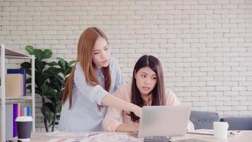 Attraktive, intelligente, kreative asiatische Geschäftsfrauen in eleganter Freizeitkleidung, die am Laptop arbeiten, während sie auf dem Schreibtisch sitzen. Lifestyle-Frauen arbeiten im Bürokonzept. foto