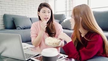 lesbisches asiatisches paar mit laptop macht budget im wohnzimmer zu hause, süßes paar genießt den liebesmoment, während es auf dem sofa liegt, wenn es zu hause entspannt ist. Lifestyle-Paare entspannen sich zu Hause. foto