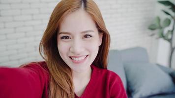 asiatische bloggerin, die zu hause im wohnzimmer vlog-videos mit dem smartphone aufzeichnet, genießen sie lustige momente, während sie auf dem sofa liegen, wenn sie sich zu hause entspannen. Lifestyle-Blogger, der zu Hause Videos macht. foto