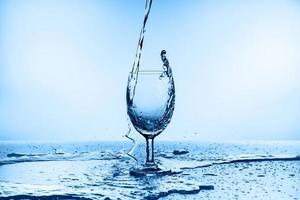 Spritzwasser aus Glas isoliert auf blauem Hintergrund