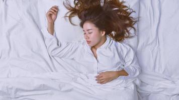 junge Frau, die im Bett schläft. Blick von oben auf die junge Frau, die sich hinlegt und gut im Bett schläft. Schlafen entspannen, junge lächelnde hübsche Dame liegt im Bett. foto