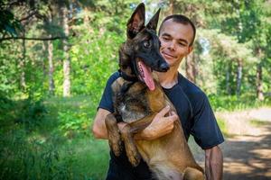 Der junge kaukasische Hipster verbringt an einem sonnigen Sommertag Zeit mit seinem Hund im Park. das Konzept eines Haustieres als Familienmitglied foto