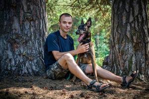 Der junge kaukasische Hipster verbringt an einem sonnigen Sommertag Zeit mit seinem Hund im Park. das Konzept eines Haustieres als Familienmitglied foto