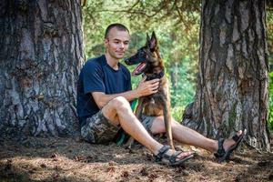 Der junge kaukasische Hipster verbringt an einem sonnigen Sommertag Zeit mit seinem Hund im Park. das Konzept eines Haustieres als Familienmitglied foto