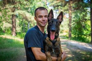 Der junge kaukasische Hipster verbringt an einem sonnigen Sommertag Zeit mit seinem Hund im Park. das Konzept eines Haustieres als Familienmitglied foto