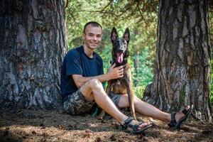 Der junge kaukasische Hipster verbringt an einem sonnigen Sommertag Zeit mit seinem Hund im Park. das Konzept eines Haustieres als Familienmitglied foto